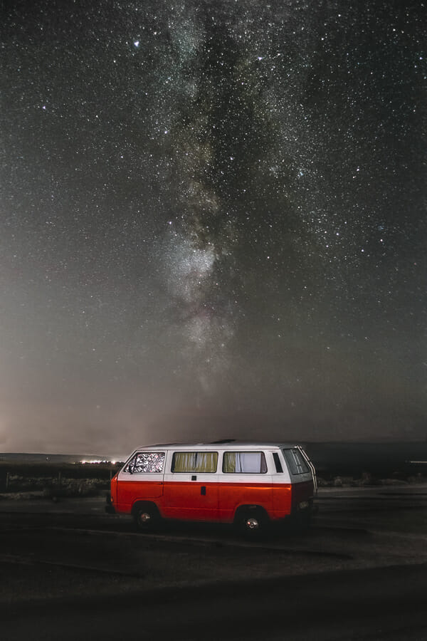 A night photo of the Milky Way over a campervan