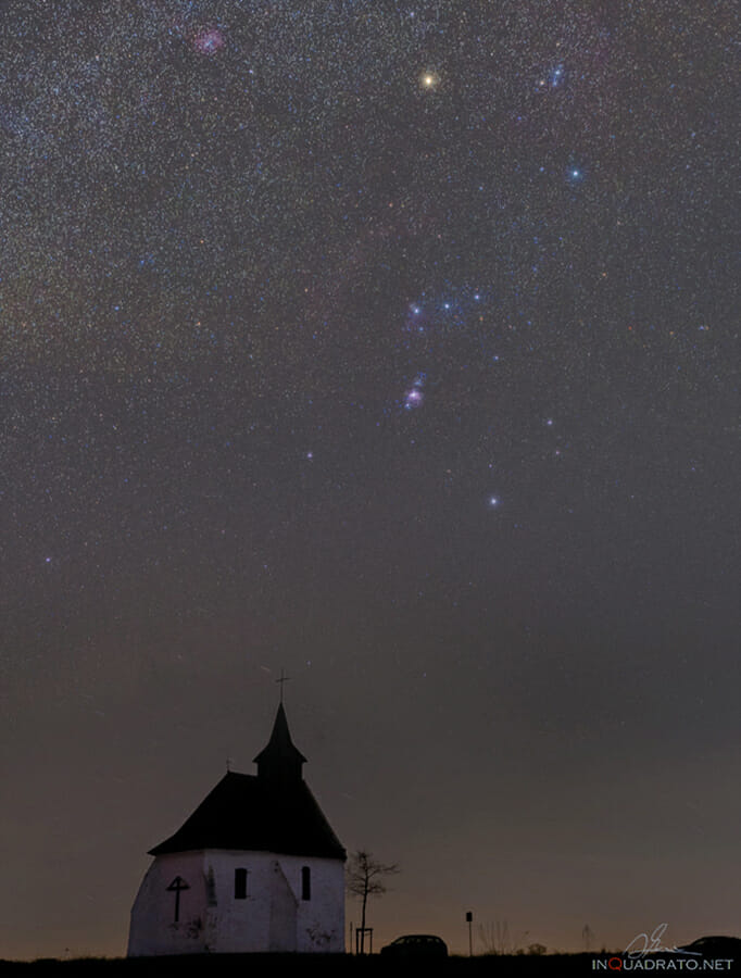 The night shot of the Orion constellation above a small church in Belgium countryside